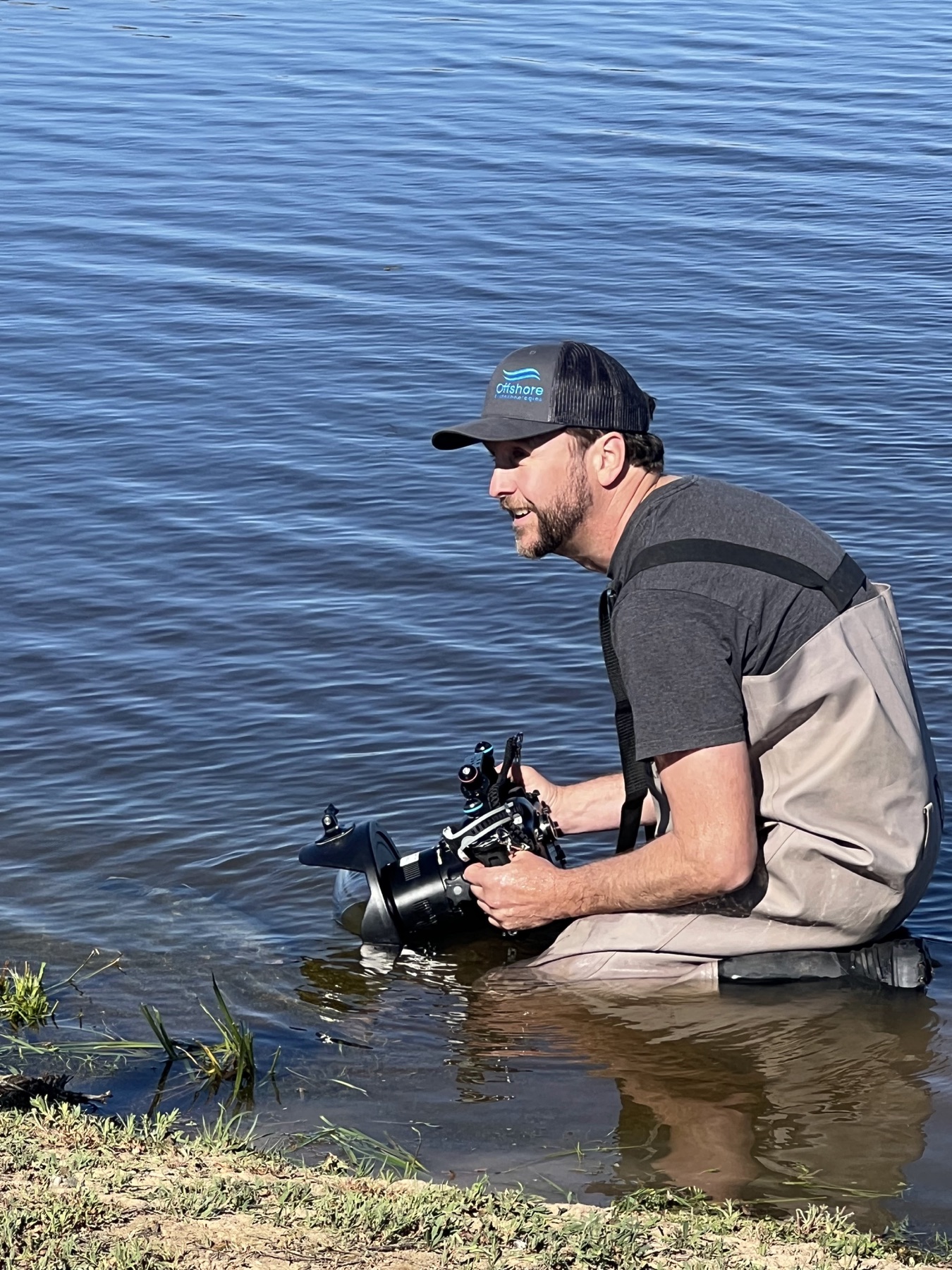 Jarrod Boord filming at the water’s edge with an underwater camera