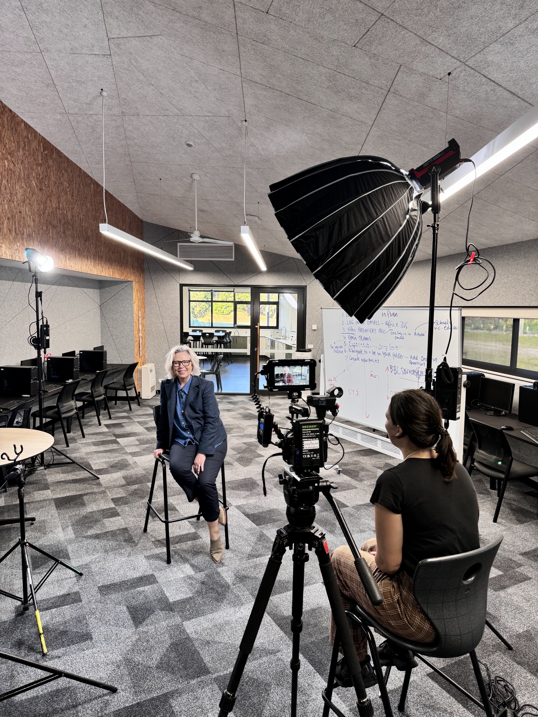 Behind the scenes of a filmed interview, with a cinema camera and lighting setup